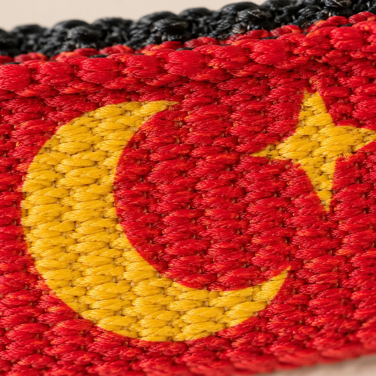 Extreme macro of the red woven webbing showing a gold moon and star printed into the weave