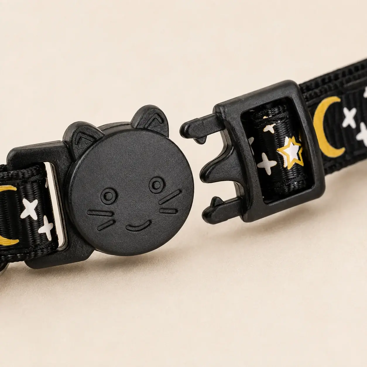 Close-up of the black cat-head breakaway buckle, shown open with the two halves separated