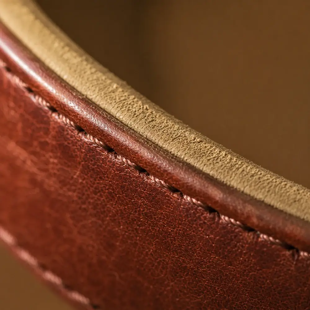Macro of the taupe lining running along the inner edge of the curved brown strap