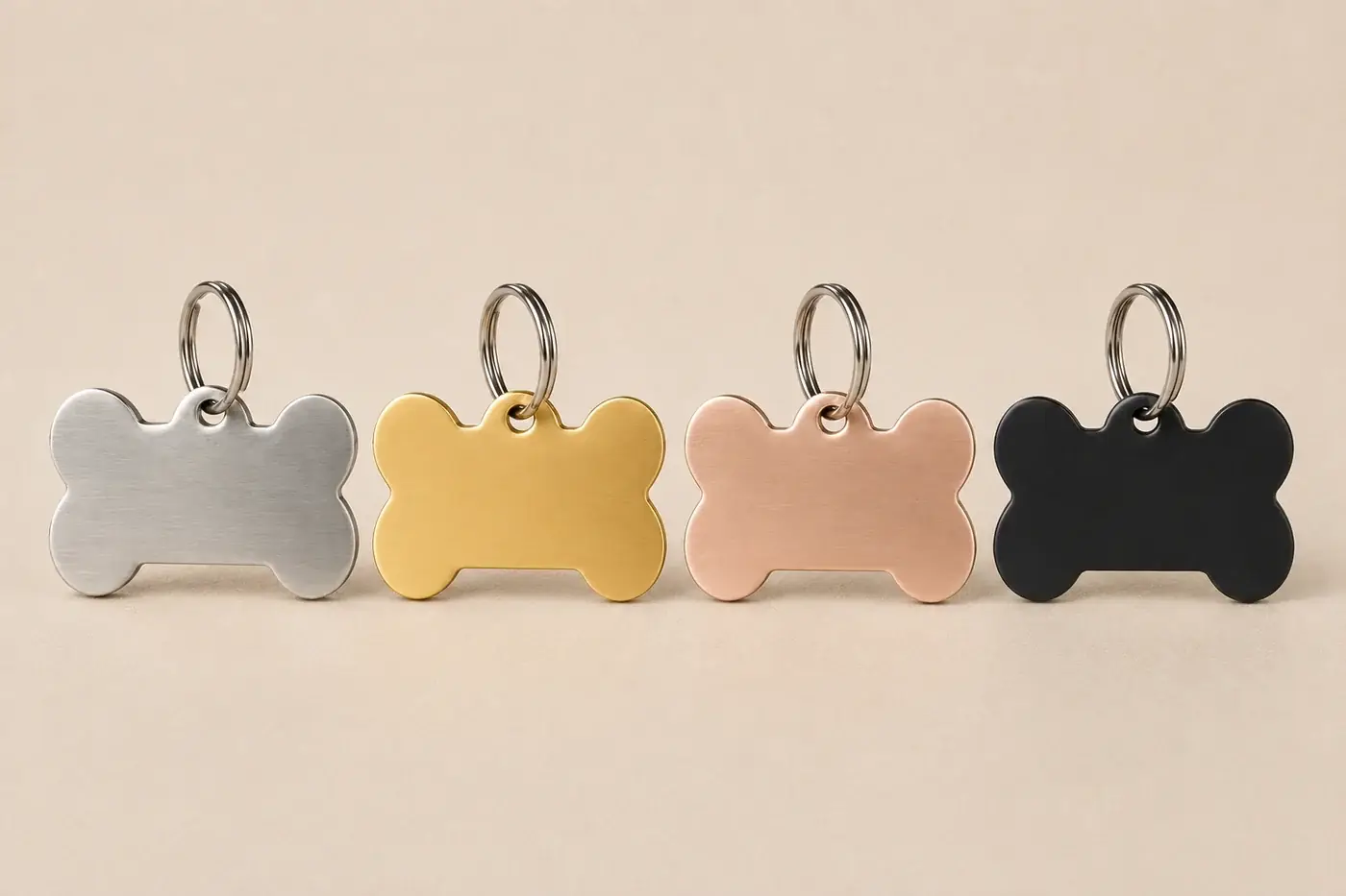 The four finishes of the bone tag lined up on split rings: steel, gold, rose gold and black