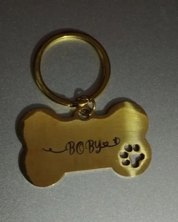 Brass bone-shaped tag engraved "BOBY", hanging from a gold split ring