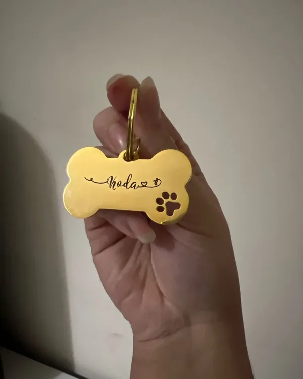 Small gold bone-shaped tag held between finger and thumb